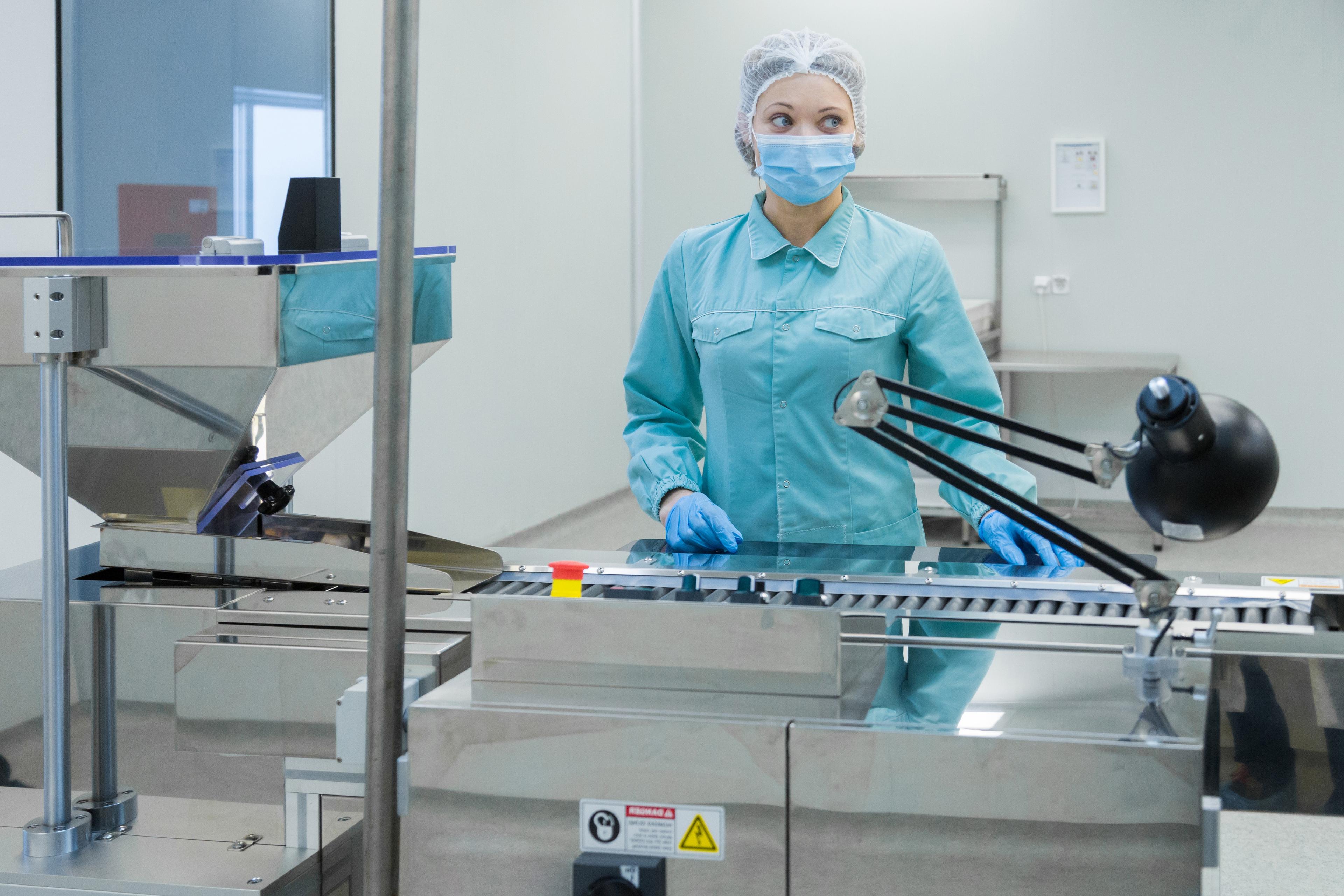 pharmacy-industry-woman-worker-in-protective-clothing-operating-production-of-tablets-in-sterile-working-conditions.jpg